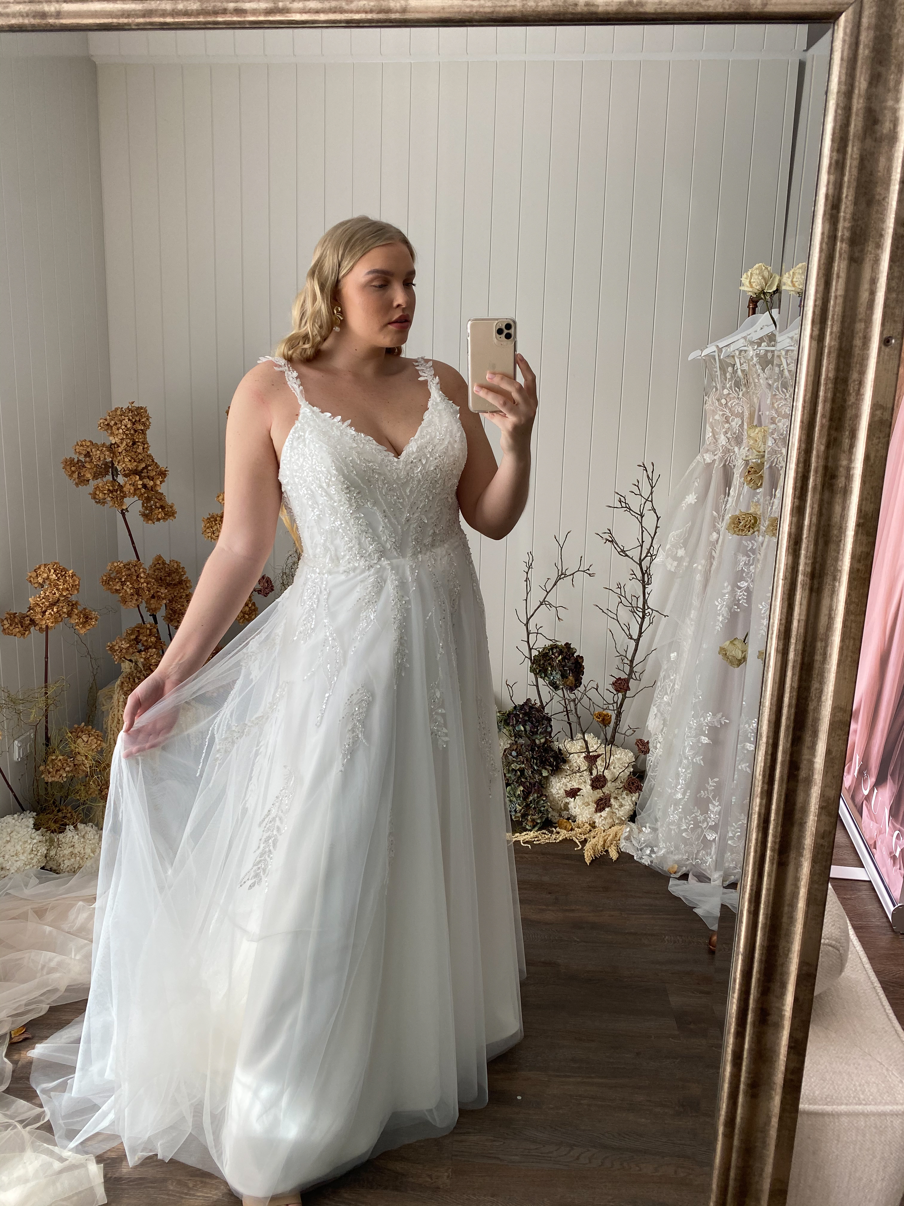 Plus Size Braut präsentiert Brautkleid vor dem Spiegel