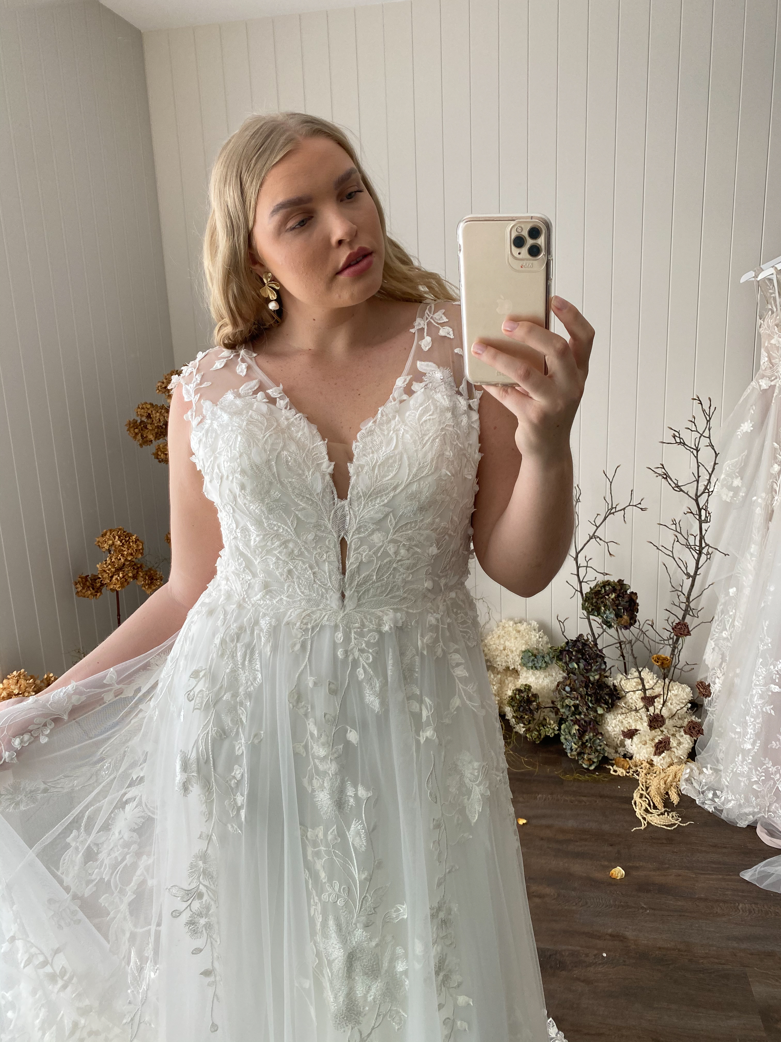 Curvy Braut macht ein Foto von sich im Brautkleid 